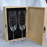 Caja de madera de boda abierta con interior forrado en terciopelo negro y copas grabadas con nombres y fecha